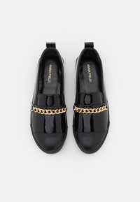 Black patent leather slip-on shoes featuring a flat sole and a gold chain accent across the front. Smooth finish and rounded toe design.