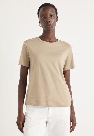 T-shirt in cotone beige con collo a giro, maniche corte e un piccolo logo ricamato sul petto. Tessuto morbido, vestibilità relaxed.
