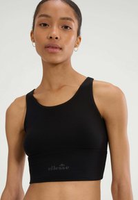 Czarny sportowy crop top z prążkowanej tkaniny, z szerokimi ramiączkami, z subtelnym wytłoczonym logo na dole. Gładka faktura, dopasowany krój, minimalistyczne detale.