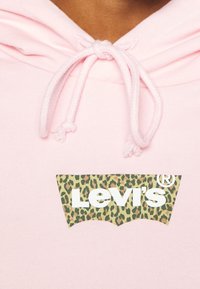 Felpa rosa chiaro con cappuccio regolabile e una toppa rettangolare con il logo Levi's in stampa leopardata bianca. Tessuto in cotone morbido.