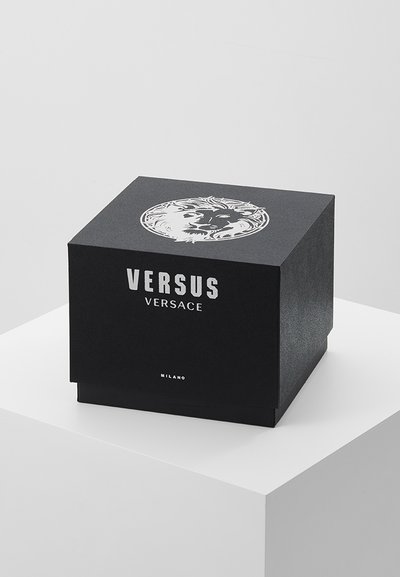 Boîte-cadeau carrée noire avec une surface texturée, ornée d'un motif de lion blanc sur le couvercle et « VERSUS VERSACE » imprimé en lettres majuscules.