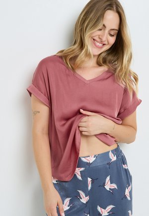 Top à manches courtes en V en tissu rose pâle, avec une coupe décontractée. Associé à un pantalon bleu orné de motifs de grues blanches.