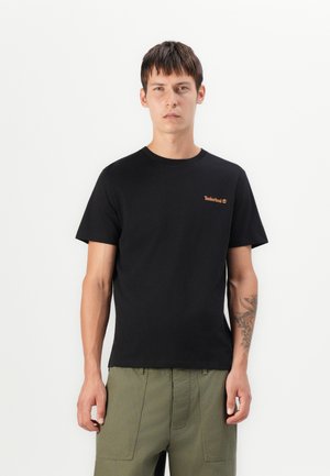 T-shirt en coton noir avec un col rond, des manches courtes et un logo Timberland embossé marron sur la poitrine gauche.