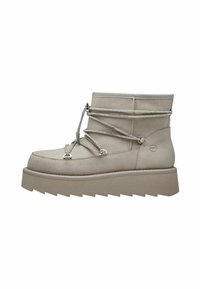 Bottes beiges à la cheville avec une finition texturée, présentant des lacets métalliques et une semelle épaisse et chunky pour la stabilité et le confort.
