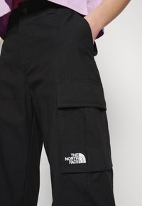 Svarta cargo-byxor med en framträdande sidficka och broderad logotyp. Tillverkade av ett texturerat tyg med en avslappnad passform.