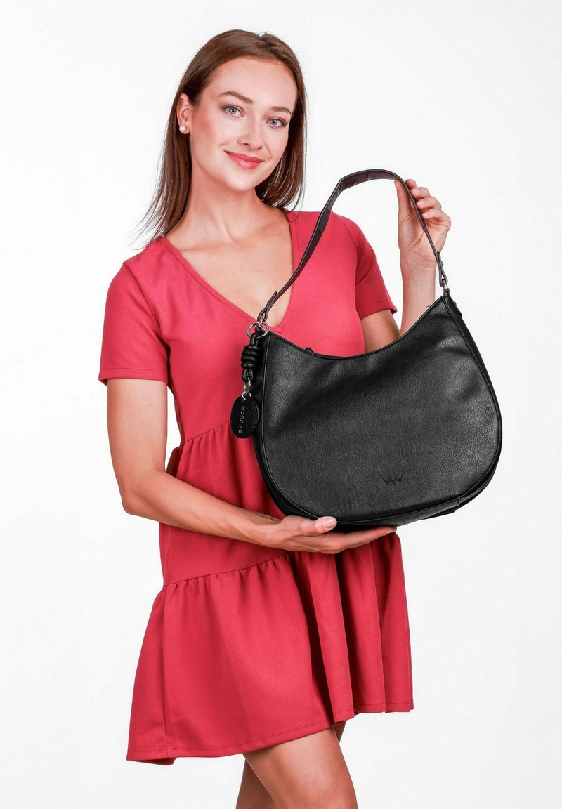 Černá kožená hobo taška s hladkým povrchem, zaobleným tvarem a dlouhým popruhem; obsahuje štítek s logem a jednoduché stříbrné kovové detaily.