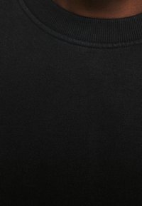 Sudadera de punto negra con un cuello redondo acanalado, que presenta una textura suave y una vista en primer plano de la tela.