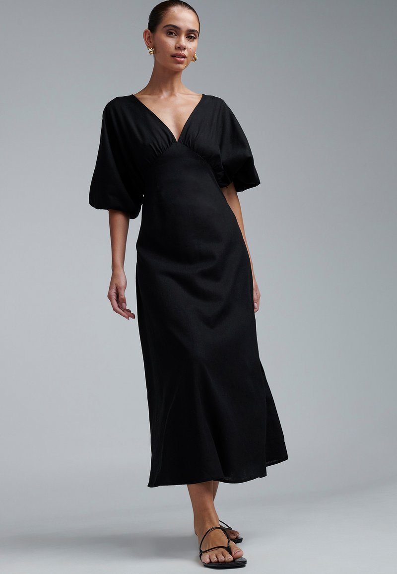 Black midi dress with a V-neckline and puffed sleeves. Made of smooth fabric, it features a fitted bodice and flared skirt design.