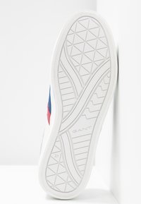Białe sneakersy z niebieskimi i czerwonymi akcentami. Gumowa podeszwa z geometrycznym wzorem bieżnika. Nazwa marki "GANT" wytłoczona blisko pięty. Rozmiar 37.
