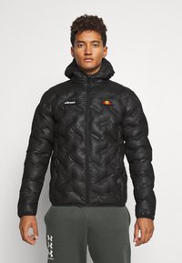 Schwarze Pufferjacke mit glänzender Textur, featuring einen Reißverschluss vorne, Kapuze, rautenförmiges Steppmuster und ein buntes Logo auf der Brust.