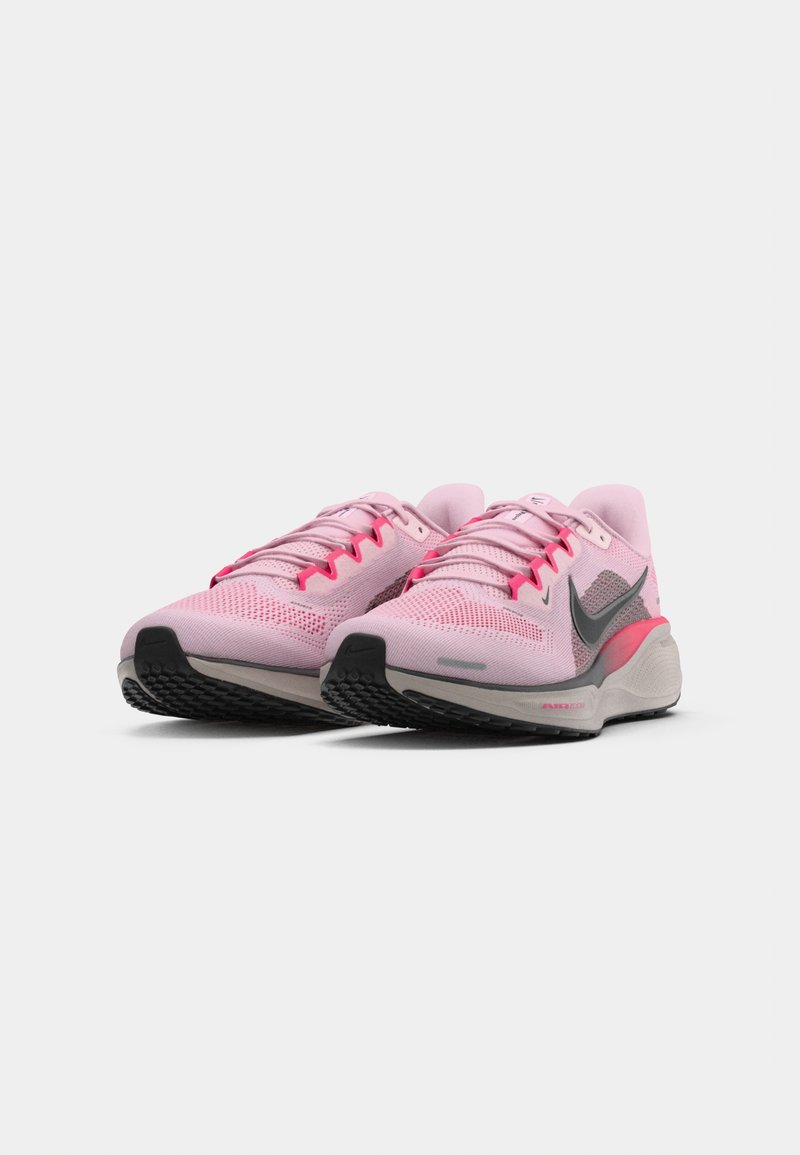 Light pink athletic shoes with mesh upper, black swoosh, and grey sole. Features bright pink accents and flat laces.