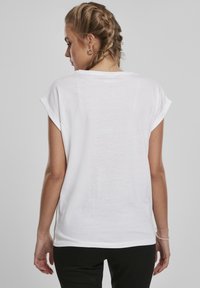 Valge, kerge T-särk lühikeste rullitud varrukatega ja lõdva lõikega. Sile tekstuur, veidi läbipaistev kangas ja ümar alläär.