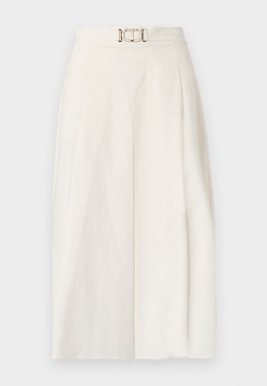 Pantaloni a gamba larga in tessuto di cotone bianco. Presentano un'alta vita con una piega frontale e un dettaglio con fibbia metallica. Texture liscia.