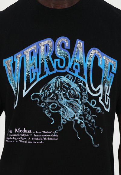 Black short-sleeve T-shirt featuring a blue jellyfish graphic and sparkling rhinestone accents. "VERSACE" printed in bold letters above.