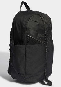 Sac à dos en tissu noir avec une forme arrondie, doté d'une poche en maille, de coutures blanches contrastées et d'une poignée supérieure pour le transport.