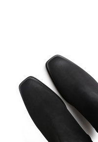 Botas de cuero negro con punta cuadrada, textura suave y costuras mínimas, con un diseño elegante sin cierres visibles.