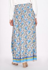 Floral Maxi-Rock mit gerafftem Bund aus leichtem Stoff, der blaue und gelbe Muster und einen blauen dekorativen Saum am unteren Ende aufweist.