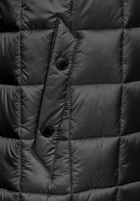 Černá péřová bunda z látky s prošívaným vzorem, s ostrými klopami a dvěma lesklými černými knoflíky. Hladká, lehká textura.