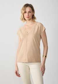 Beige cotton blend V-neck t-shirt with short sleeves, featuring a relaxed fit, subtle stitching details, and smooth texture.