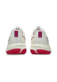 Vita atletiska skor med en strukturerad ovandel, med röda accentfärger på hälen och sulan, samt ett hexagonalt mönster på sidorna.