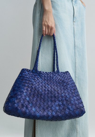 Υφασμένη τσάντα tote από σκούρο μπλε δέρμα με υφή, διαθέτει δύο πλεχτούς χειρολισθήρες και ευρύχωρο, χαλαρό σχέδιο.
