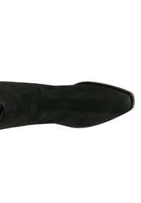 Bottine noire en daim avec un bout pointu et un design épuré. La surface est lisse, sans matériel visible ni embellissements.