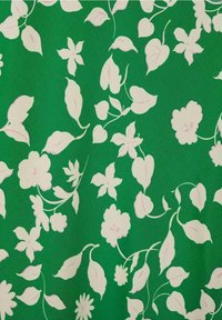 Tessuto verde con un motivo floreale che presenta foglie e fiori rosa di varie dimensioni. Texture liscia con un design coerente in tutto il tessuto.