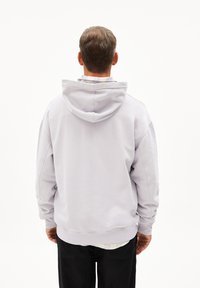 Hoodie gris clair avec capuche à cordon, coupe décontractée, poignets et ourlet côtelés, porté sur une chemise à carreaux, affiché de dos.