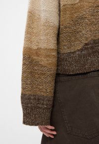 Πλεκτό πουλόβερ με οριζόντιες ρίγες σε διάφορες αποχρώσεις του μπεζ και του καφέ. Υφή υφάσματος με ριχτό μανίκι και χοντρό στρίφωμα.