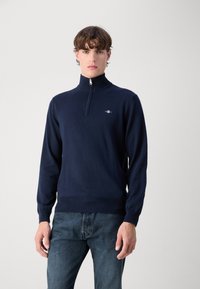 Pulover din tricot de tip quarter-zip în nuanța bleumarin, cu mâneci lungi, tiv ribbed și un logo mic pe piept.
