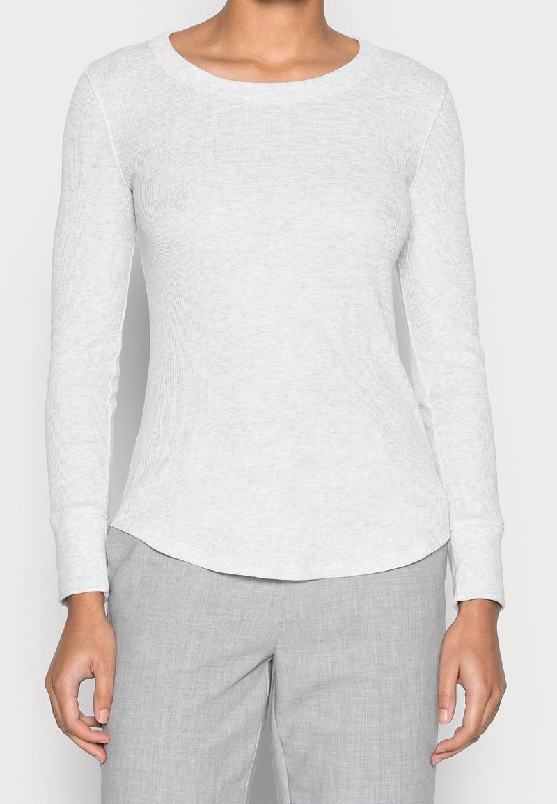 Long-sleeve, light gray ribbed t-shirt with a rounded neckline and slightly curved hem. Features fitted sleeves and soft fabric texture.