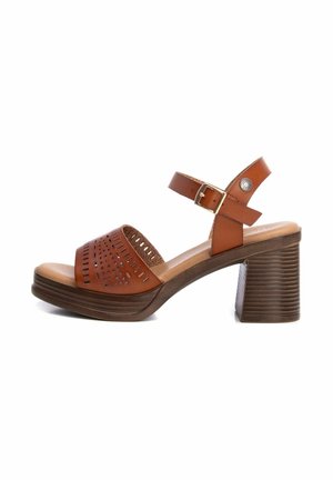 Sandalias de cuero marrón con tacón, diseño de parte superior perforada, correa ajustable en el tobillo y tacón en bloque marrón texturizado.