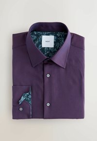 Ciemnofioletowa koszula z długim rękawem o teksturowanej powierzchni, z niebieskim kołnierzem i mankietami w kwiatowy wzór, oraz dwoma guzikami z przodu.