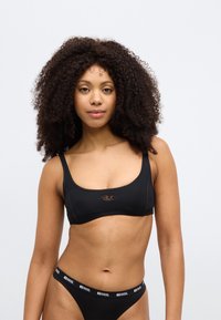 Juodos spalvos bikini viršus su kvadrato formos iškirpte, centre su mažu logotipu, derinamas su juodos spalvos bikini apačia su prekės ženklo diržu.