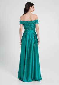 Abito da sera teal con scollo off-the-shoulder, corpino in paillettes e gonna in satin fluente con pieghe.