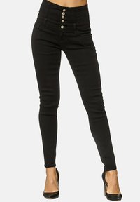 Hoch taillierte schwarze Jeans aus Denim mit glatter Textur, ausgestattet mit einer Fünf-Knopf-Verschluss und Slim Fit, kombiniert mit schwarzen Absätzen.