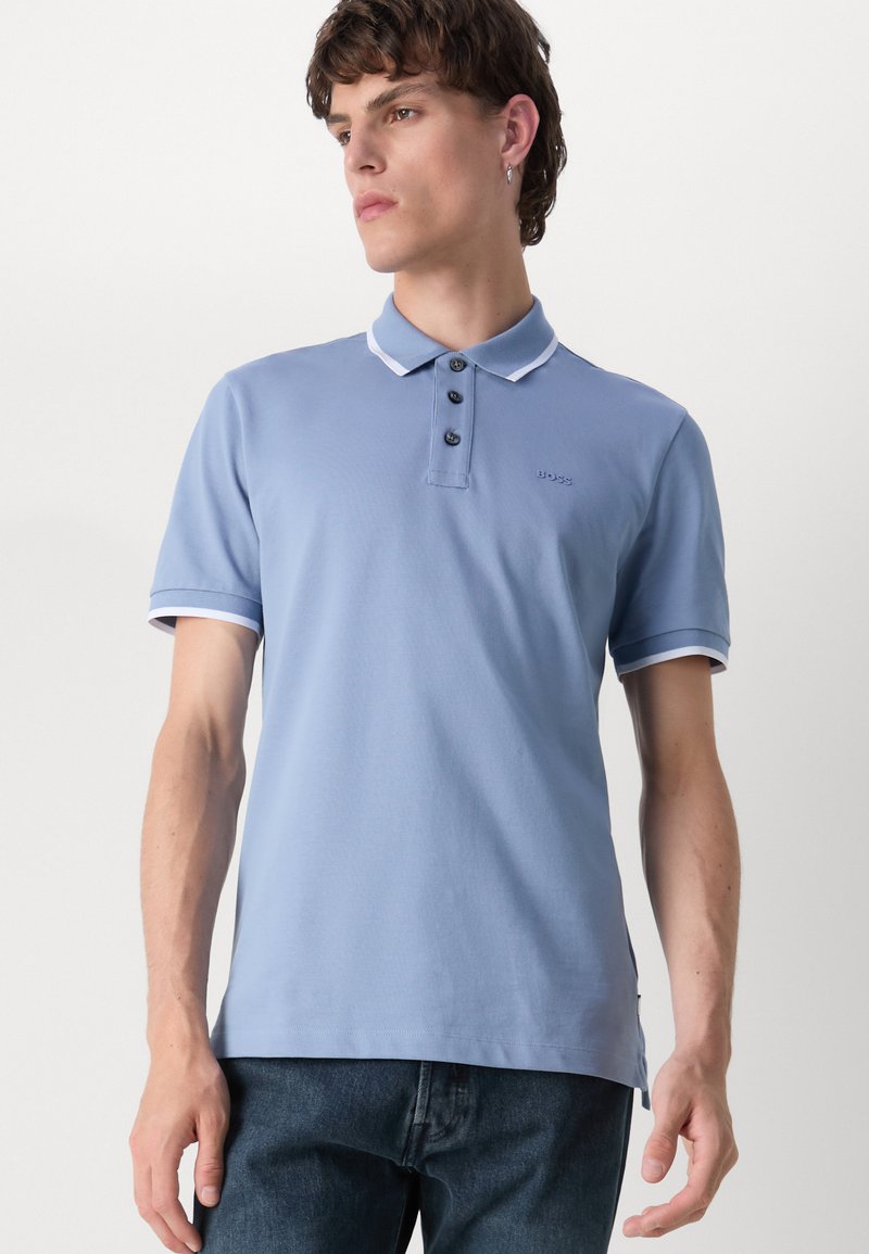 Polo léger bleu avec trois boutons, col et bord de manche blancs contrastants, logo brodé sur la poitrine et manches courtes.