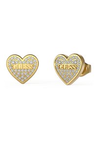 Orecchini a forma di cuore color oro, con rhinestone trasparenti e il logo "GUESS" impresso al centro.