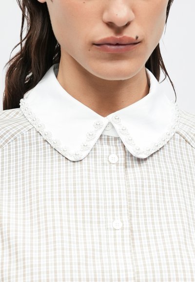 Button-up shirt featuring a white collar with small pearl-like embellishments. The body has a tan and white checkered pattern with a smooth texture.