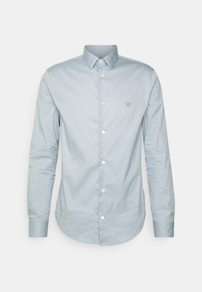 Hele sinine pikapaistega nööbiga särk, mis on valmistatud siledast kangast, millel on klassikaline krae, valged nööbid ja väike logo rinnal.