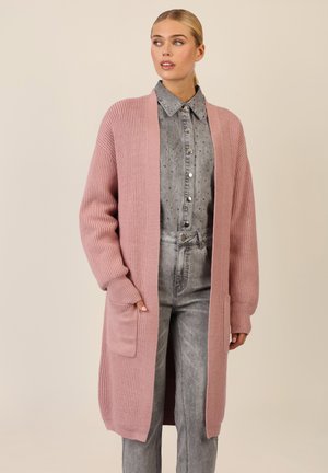 Long pink cardigan made of ribbed knit fabric, featuring open front, long sleeves, and two front pockets. Worn over a denim shirt.