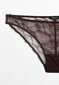Hnědé krajkové kalhotky s jemným květinovým vzorem, s průsvitnou krajkou v přední části a pevným materiálem na zadní straně.
