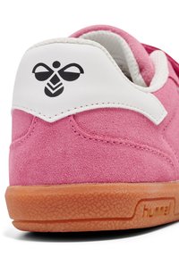 Sneaker in suede rosa con sovrapposizione del tallone in sintetico bianco e suola in gomma color caramello. Presenta un logo nero stampato sul tallone.