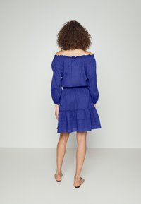 Blå off-shoulder klänning i lätt tyg, med långa puffärmar, volangkjol och samlad midja med ornamenterad sömnad.