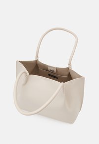 Sac à main en cuir couleur crème avec poignées arrondies, rabat supérieur ouvert et poche intérieure avec fermeture magnétique.