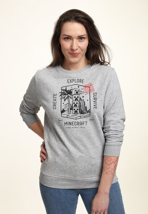 Szary sweter z grafiką Minecraft przedstawiającą wieżę, palmy oraz napisy "TWÓRZ", "ZBAWIAJ" i "PRZETRWAJ". Długie rękawy i okrągły dekolt.