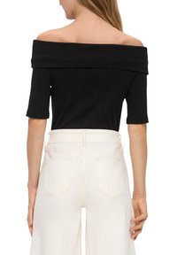 Czarna bluzka typu off-the-shoulder z krótkimi rękawami, o prążkowanej fakturze, połączona z jasnoniebieskimi spodniami z wysokim stanem i szerokimi nogawkami, z tylnymi kieszeniami.