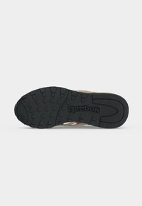 Подметка на обувка Reebok, показваща черна гумена шарка с кръгови и линейни мотиви и логото на Reebok в центъра.