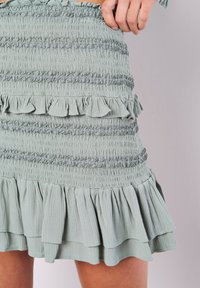 Ljusgrön, smockad minikjol med lager av volanger vid fållen, som har textil med struktur och elastisk midja för en åtsittande design.
