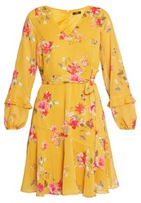 Blommig omlottklänning i senapsgul, med långa puffärmar, volangmanchetter, ett bälte i midjan och en flerlagers kjolslut.